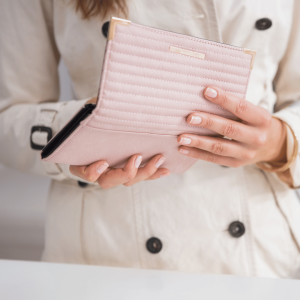 woman in a white coat holding a pink wallet to demonstrate the affordability of working with a clinical intern student therapist